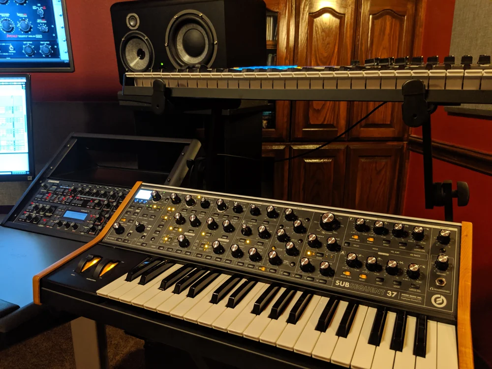 Analog synthesizer controls in the warm wood-lined TASADI studio